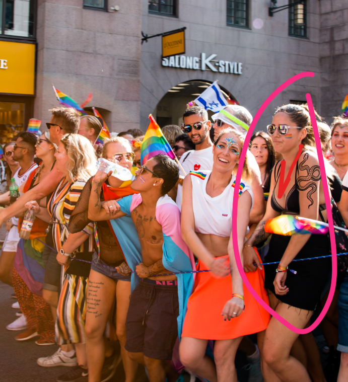Photo of people in a crowd at pridefest. One person is circled and wearing a red lanyard